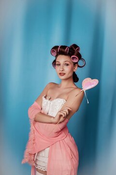 Model poses with candy heart in studio setting during fashion shoot with blue backdrop