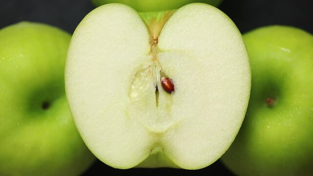 Half of green apple on a rotating pile of apples against a black background. Top view shot