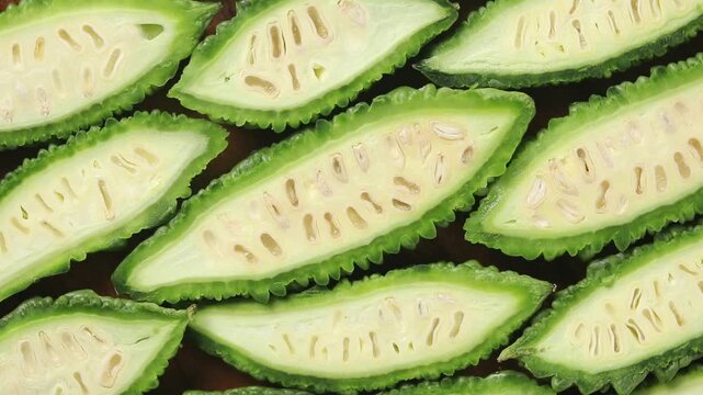 Halved fresh bitter melons arranged side by side, rotating, Top view shot