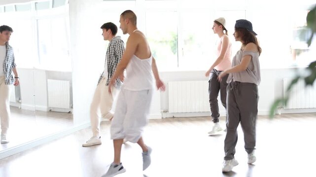 Active young guys and girls practicing hip-hop reject step in training hall during dancing classes. High quality 4k footage