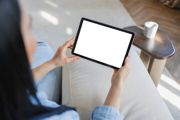 Woman holding tablet with blank white screen on sofa at home, mockup for app or advertising, digital lifestyle, online shopping, communication and cozy apartment concept © InsideCreativeHouse