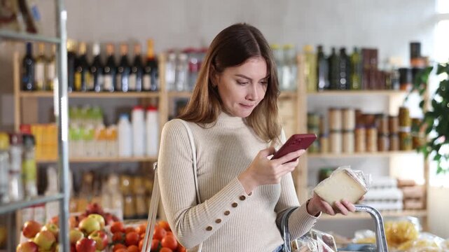 Young female shopper scanning qr code for packaged cheese in grocery store