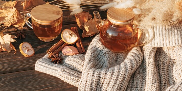 Warm fall tea still life background with teapot cup on knit sweater and dried spices for cozy banner and poster design