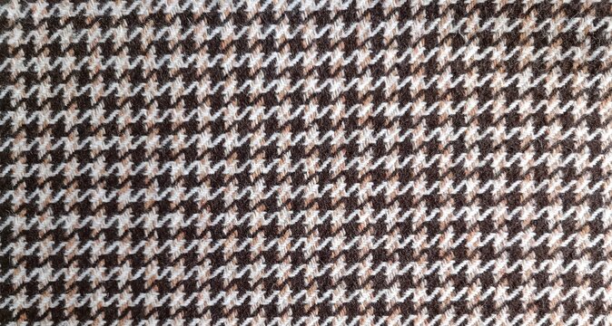 Macro of brown, beige, and white hounds tooth pattern with jagged interlocking four pointed checks. Slightly napped, fuzzy wool texture adds warmth and depth.