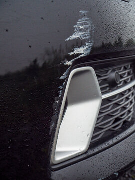 Black car with white scratch marks damage to its fine surface. Car accident or bad driving concept. Wear and tear. Cost and price of repair the damage. Waiting for insurance claim theme.