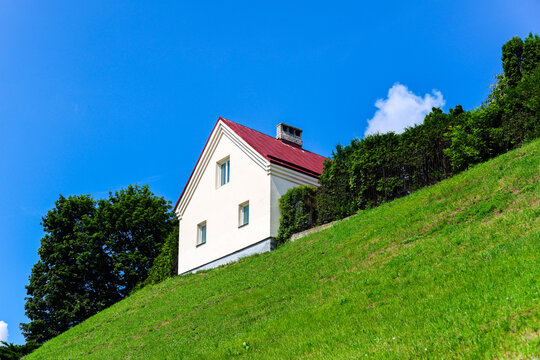 Beautiful white lonely house on top of high green mountain hill against blue sky with clouds, solitary residential home in nature landscape.