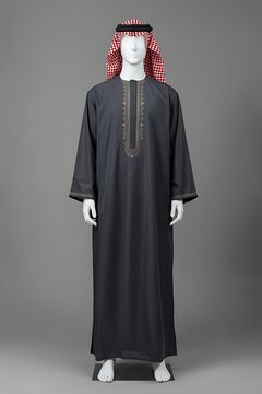 Traditional arabic mens thobe or dishdasha in dark grey with intricate embroidery on the chest and cuffs, worn with a red and white checkered ghutra and black agal on a mannequin