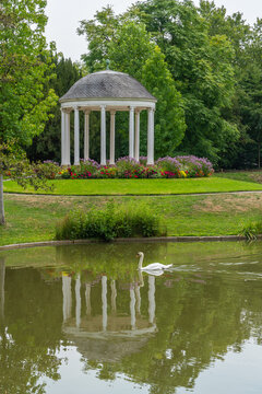 White pavilion in a blooming garden with a pond and a swan in the water. a round, shaded shelter in the Parc de l'Orangerie in Strasbourg.