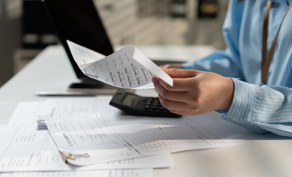 Businesswoman reviewing receipts and financial documents with calculator and laptop, highlighting expense tracking, bookkeeping, tax preparation, accounting workflow and business finance management.