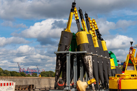 Yellow and black cardinal navigation buoys stored on land for maintenance in Port of Hamburg, maritime safety concept