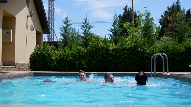 Happy family swimming, splashing water, and having fun in an outdoor pool while a Jack Russell terrier dog runs along the poolside on a sunny day