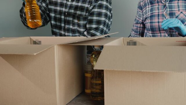 Volunteers wearing gloves pack food items into boxes for donation during pandemic crisis.