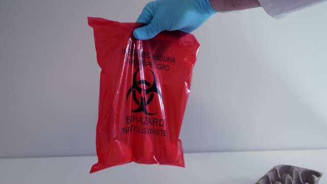 Inspector in lab coat and gloves placing eggs in red biohazard bag, representing Salmonella outbreaks, food recalls, and factory farming safety risks
