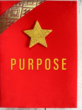 Minimal motivational concept featuring the word &ldquo;Purpose&rdquo; on a red notebook with a gold star, symbolizing personal growth, meaningful goals, direction and intentional living.