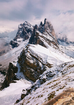 Dramatic winter view of Seceda mountain peaks in the Italian Dolomites, snow covered alpine landscape with rugged rocky cliffs, dramatic cloudy sky, panoramic nature scenery in South Tyrol, vertical