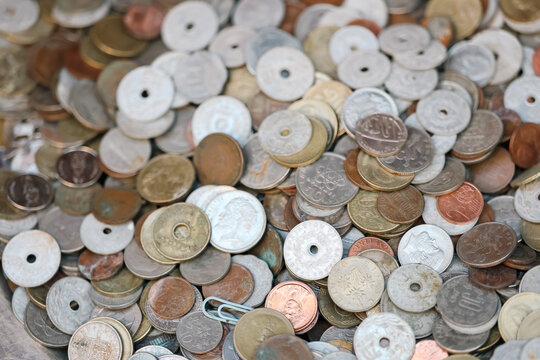 A pile of assorted vintage coins in Greece displays intricate designs and textures, reflecting historical currency and cultural heritage.