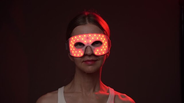 smiling woman wearing infrared light eyes therapy mask. Red and infrared light therapy eye mask.  professional biohacker theme skin care video footage