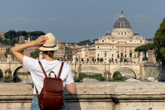 Woman enjoys a sunny Roman morning on a bridge overlooking the Vatican dome. A moment of joy and timeless travel charm