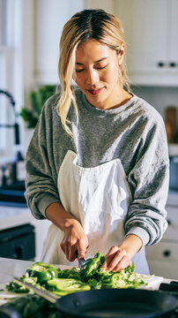 Beautiful Asian Woman Preparing Fresh Vegetables in a Bright Modern Kitchen