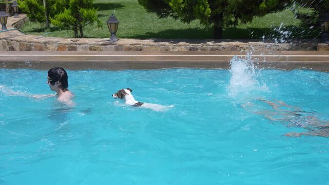 Man jumping into outdoor pool with kids and Jack Russell terrier during summer vacation