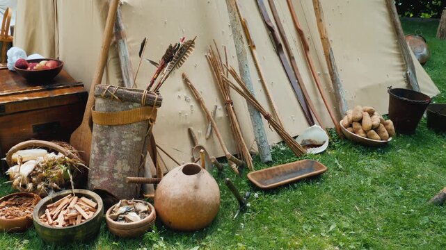 Historical reenactment of indigenous settlement with traditional hunting tools and gathered food.