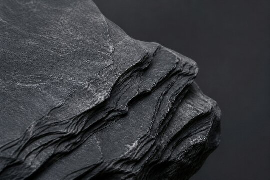 Layered slate rock displaying textured edges on dark background