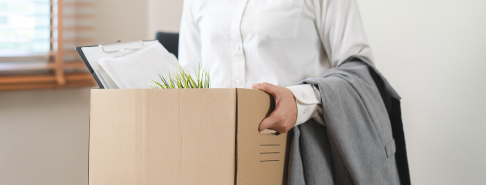 Close-up of a businessman holding a cardboard box with personal belongings after resignation.