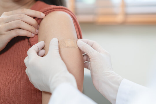 Close up of doctor applying adhesive bandage on girl arm after vaccination.