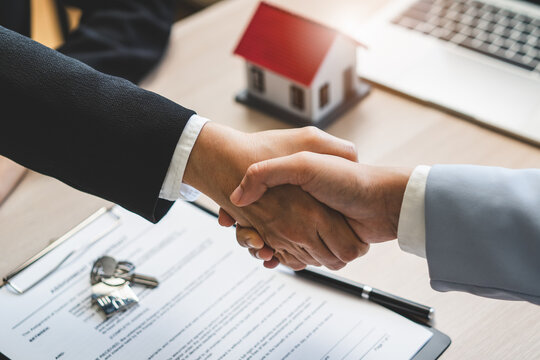 Close up of real estate agent shaking hands with client after signing contract.