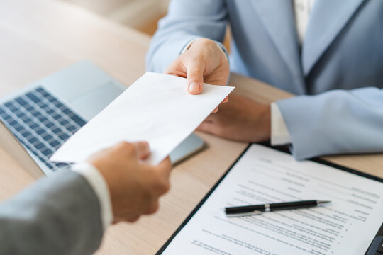 Close up of employee handing resignation letter or application to manager.