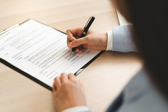Extreme close up of businessman signing official document with black pen.