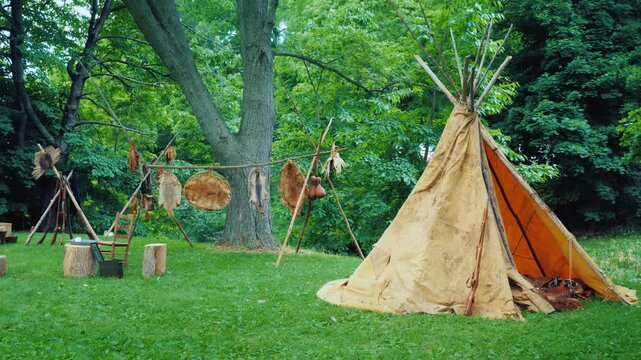Historic native american encampment with tipi and furs drying on racks.