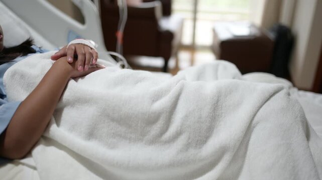 Female patient sits on a hospital bed beside an IV infusion pump while receiving medical care. Concept of hospitalization, healthcare, patient recovery, treatment, and clinical care.