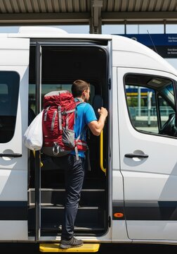 Young Male Backpacker Boarding a White Shuttle Van at a Transit Station for Travel and Adventure