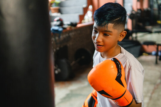 Young boy learning boxing skills with punching bag