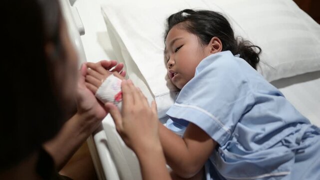 A concerned mother holds her sick child's hand while the child receives oxygen therapy in a hospital bed. Family support, pediatric healthcare, compassion, medical treatment, and hope for recovery.