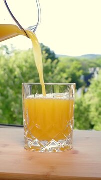 Freshly squeezed orange juice is poured into a glass; fruit contains fructose. Popular, refreshing soft drink in the summer. Refreshment, vitamin C, healthy lifestyle, non-alcoholic drink.