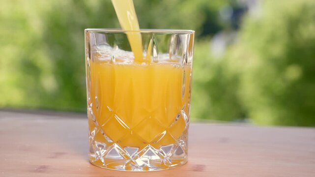 Freshly squeezed orange juice is poured into a glass; fruit contains fructose. Popular, refreshing soft drink in the summer. Refreshment, vitamin C, healthy lifestyle, non-alcoholic drink.