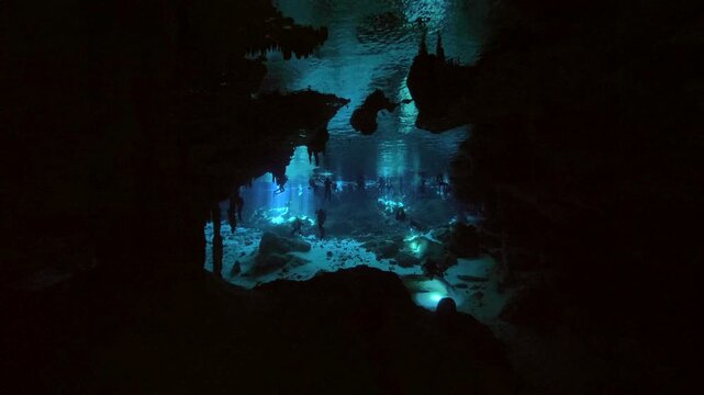 A bright irregular patch of blue water appears beyond a shadowed rock passage in Cenote Carwash, Quintana Roo, Mexico.