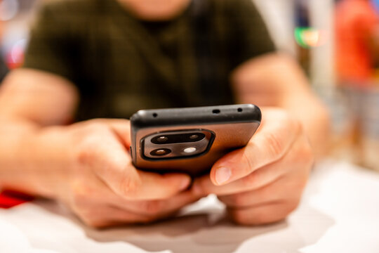 Man typing messages on mobile device during daylight at local cafe