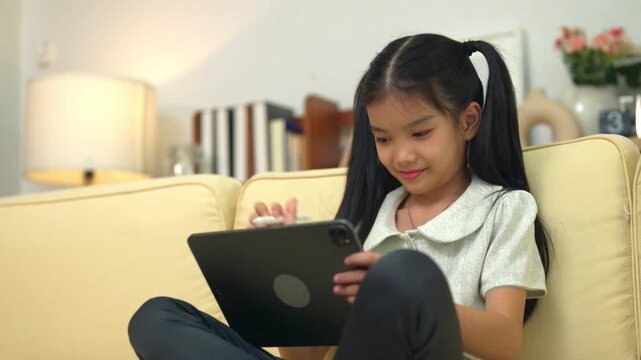 Young Girl Thinking While Using Tablet with Stylus Pen at Home on Sofa