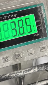 Closeup of digital flour scale display in bakery. Electronic weighing system measures ingredients with precision for commercial bread production, quality control and professional food manufacturing.