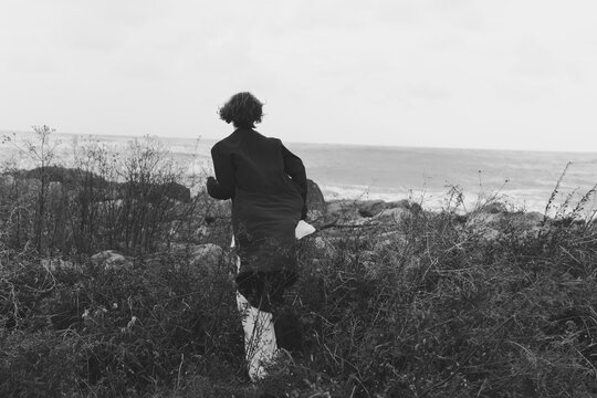 Runner, silhouette, coastal landscape and ocean view with shore and wind in motion, capturing movement across wild grass, evoking exploration, nature, and seaside serenity