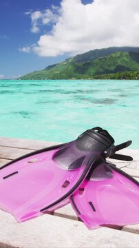 Travel holiday tropical ocean snorkel fins for swimming in coral reefs getaway, south pacific ocean. Pink female sport gear lying on deck in Tahiti, French Polynesia. Raw unedited vertical video,