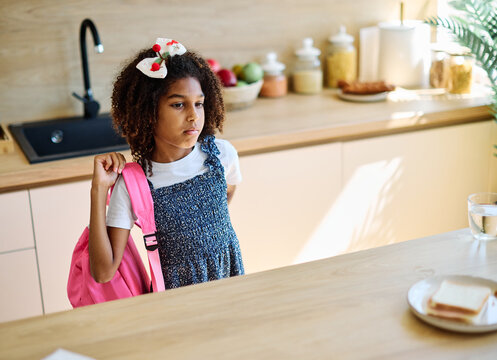 Portret of  a black girl with a school backpack having fun talone preparing sanwiches snack for  breakfast and school  in kitchen