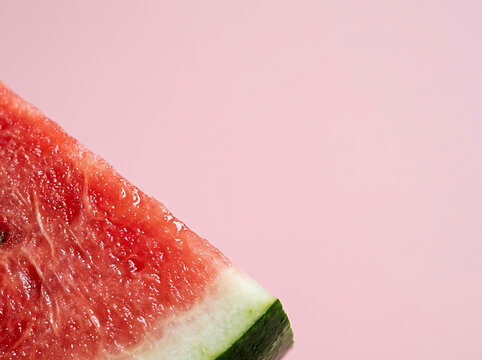 Vibrant close-up of a red watermelon slice with green rind on a pastel pink background, focusing on ripe fruit texture