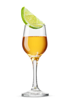 Golden tequila shot served in a stemmed glass with a fresh lime wedge isolated. Transparent PNG image.