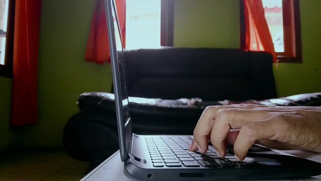 Young professional typing on laptop in cozy home workspace. Freelancer working remotely with modern computer setup in warm living room.