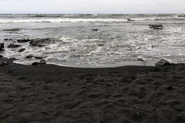 Ocean waves washing over the dark volcanic sand at Punalu'u Black Sand Beach on the Big Island Hawaii © Joao Vieira