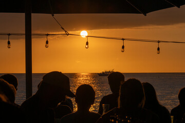Silhouetted people at an outdoor restaurant watching the sunset on the Big Island Hawaii © Joao Vieira